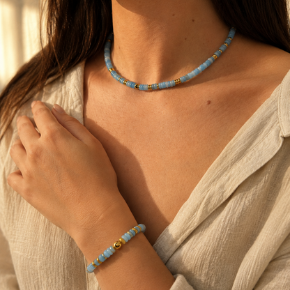 Woman wearing a blue beaded necklace and bracelet against a neutral background